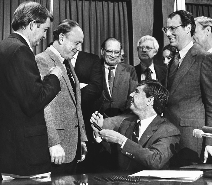 Graham hands out souvenir pens after signing the historic growth management bill that will set guidelines for Florida's growth in the future. Left to right is Sen. John Vogt, (D), Cocoa Beach; Rep. Sam Bell, (D), Ormond Beach; Community Affairs Secretary John DeGrove; and far right Sen. Patrick Neal, (D), Bradenton. (Associated Press photo)