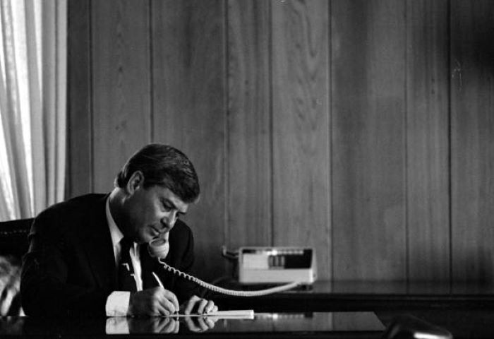 Bob Graham wearing Florida tie at his desk, on the phone and taking notes on his last day as governor