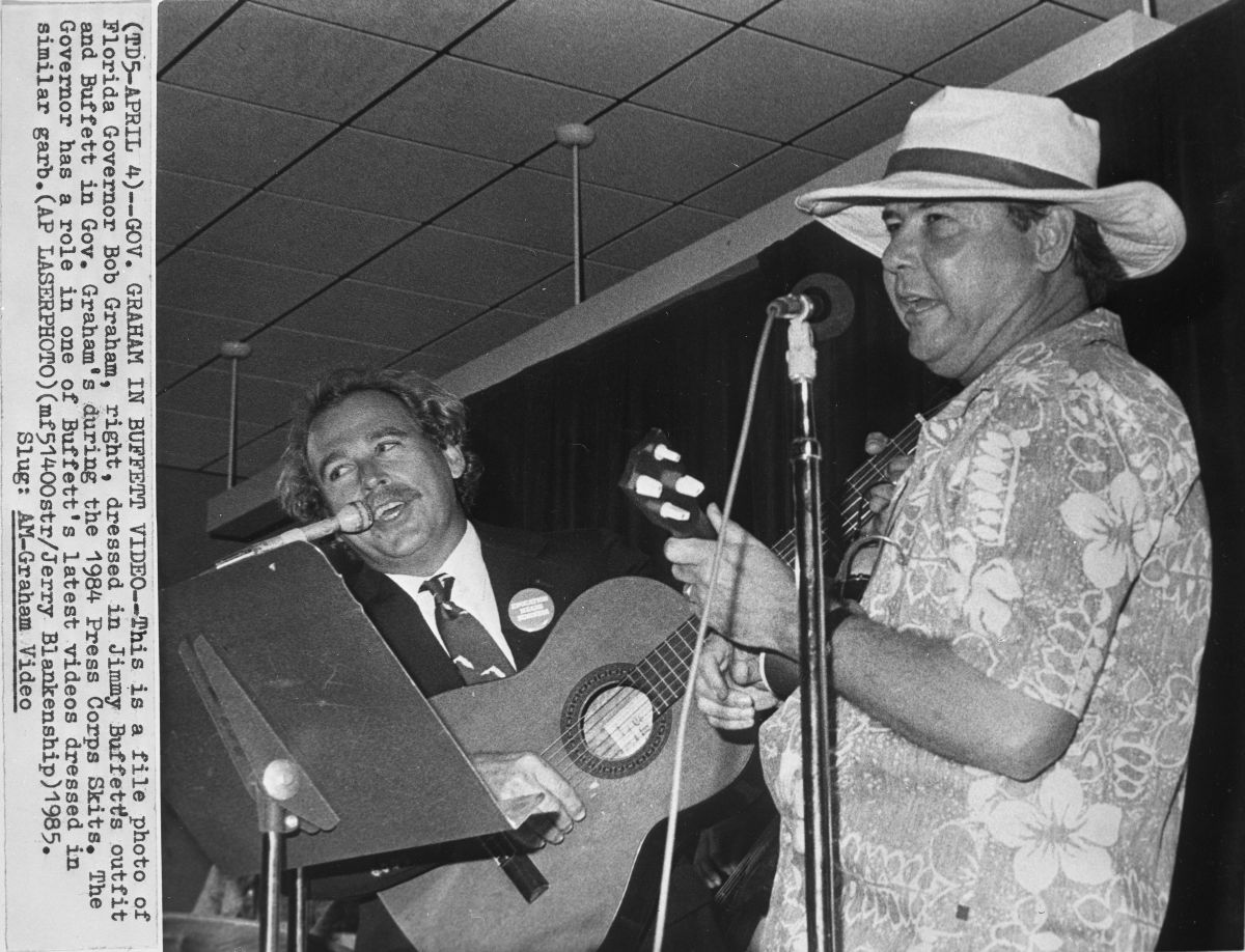 News clip of Jimmy Buffett performing with Governor Bob Graham as they wear each other's iconic styles at the 1984 Press Corps Skits.