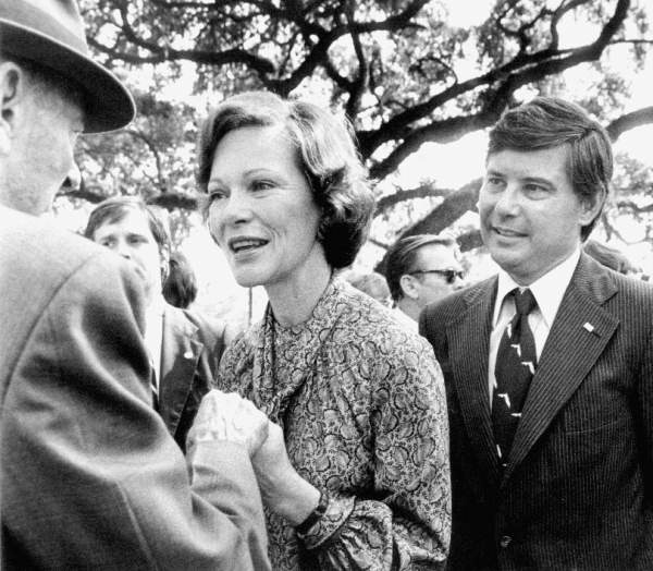 Rosalynn Carter holds the hands of 85-year-old W. M. Scruggs, Sr., speaking to him at a political rally for Bob Graham's first gubernatorial campaign. Bob Graham stands next to her, smiling.