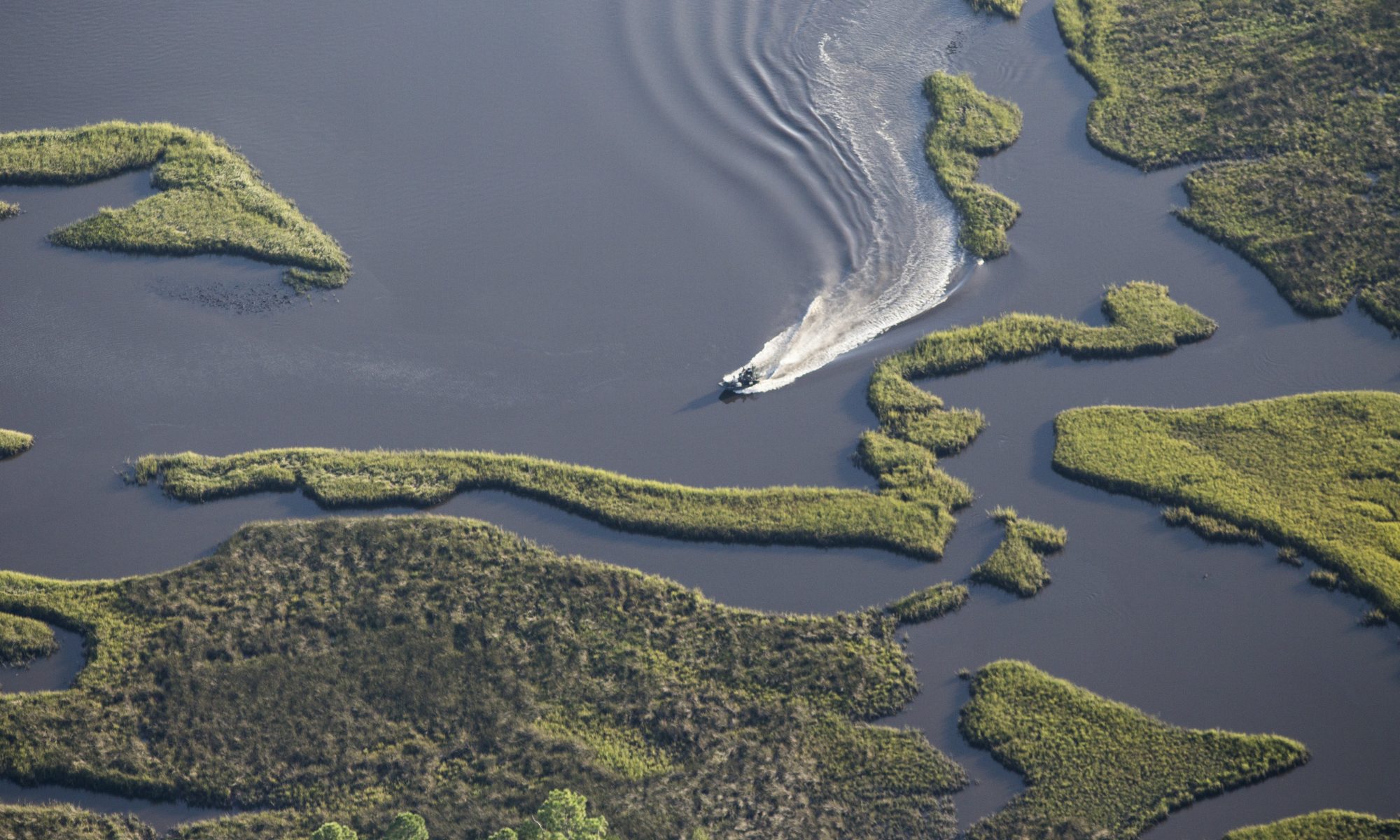 Aerial photograph of a boat navigating the tidal marsh lands off of Cedar Key, Florida.